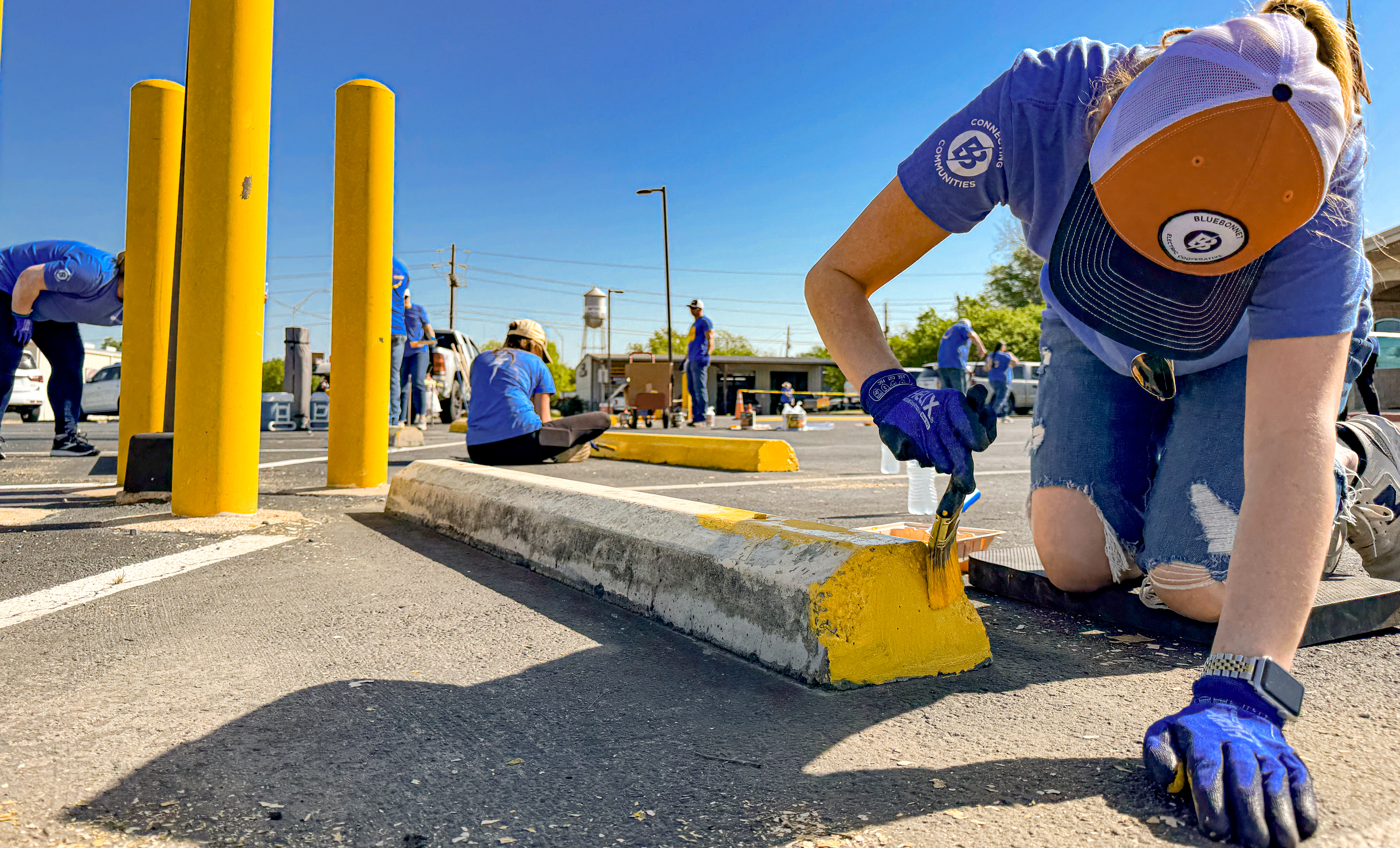 Bluebonnet employees volunteer in partnership with LCRA Steps Forward Day to repaint tire stops and speed bumps at Smithville's Community Rec Center.