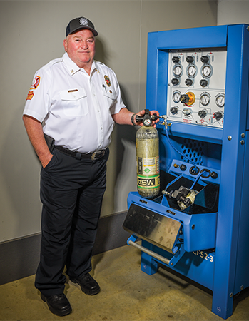 Chief Spencer Schneider, above, with the machine that can refill two oxygen tanks at a time. The device saves precious minutes in response time.