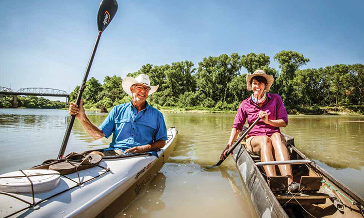 Pam LeBlanc and Jimmy Harvey paddle their boats on the Colorado River at Fisherman’s Park in Bastrop. (Sarah Beal photo)