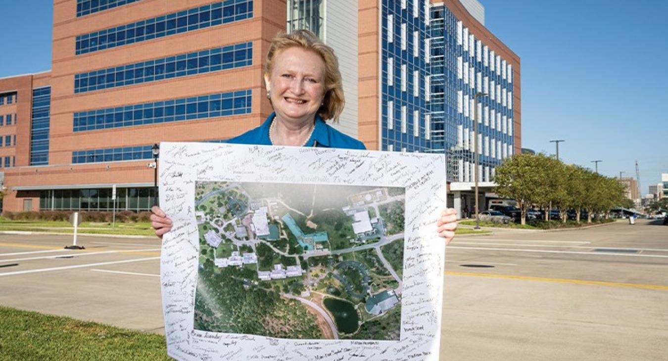 Sharon Dent was among some 50 employees who gathered for an outdoor farewell to Science Park on June 29, 2021, which included a group walk on the path looping around the site. They signed an enlarged aerial campus photo that now hangs near Dent’s office at an MD Anderson research facility in Houston. (Photo by Adolfo Chavez III, The University of Texas MD Anderson Cancer Center)