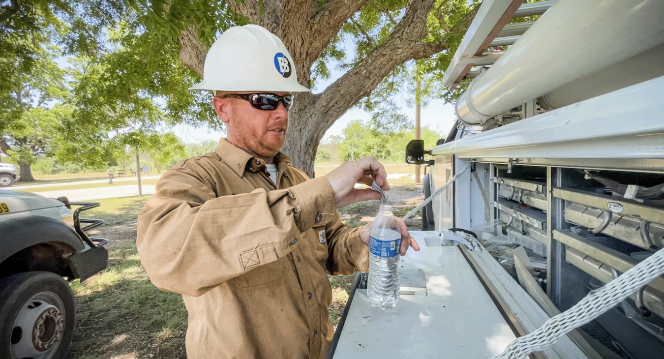Doug Grimm, a crew supervisor in Giddings, pours an electrolyte powder into a cold bottle of water to stay hydrated. The powders use an optimal sodium-to-glucose ratio that delivers water to the body faster. Sarah Beal photo