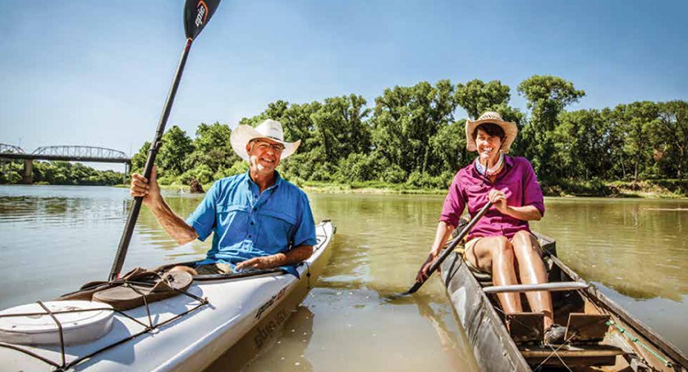 Pam LeBlanc and Jimmy Harvey paddle their boats on the Colorado River at Fisherman’s Park in Bastrop. (Sarah Beal photo)