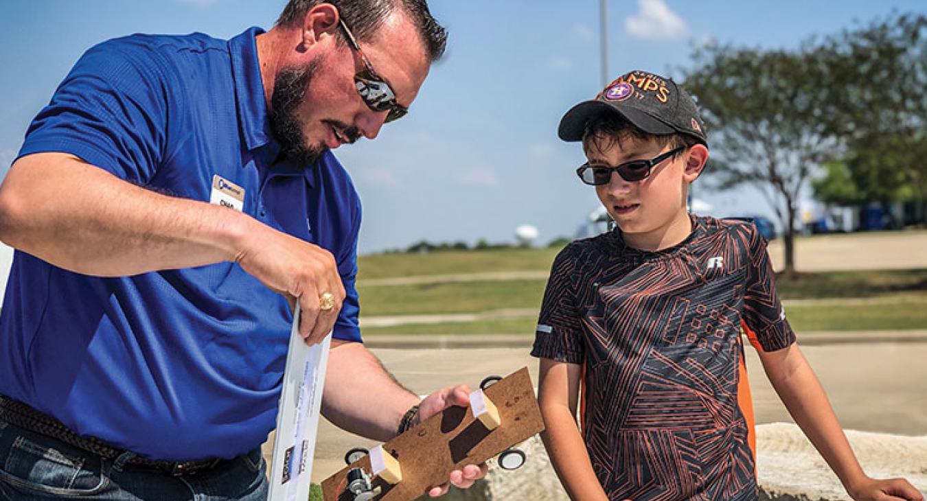 Bluebonnet’s Chad Siegmund shows Christian Pratt of Ledbetter how to assemble a mini-vehicle that can roll down the road powered by solar strips. (Photo by Sarah Beal)