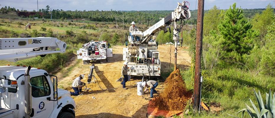 crews working in field setting pole